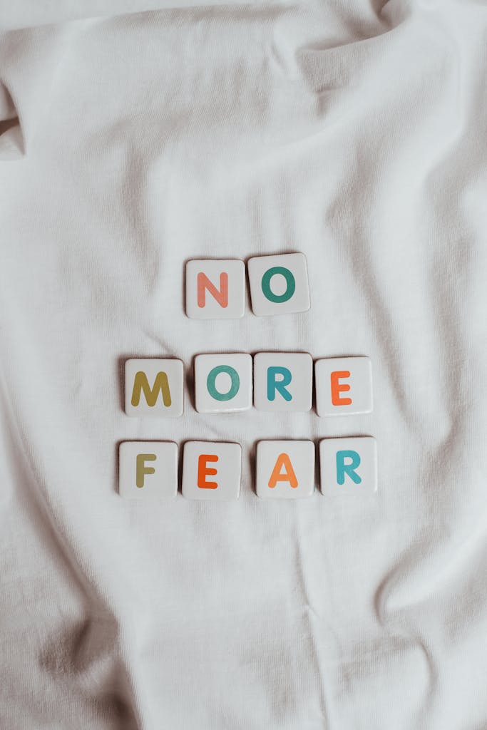Colorful letter tiles spelling 'No More Fear' placed on a soft white fabric background.
